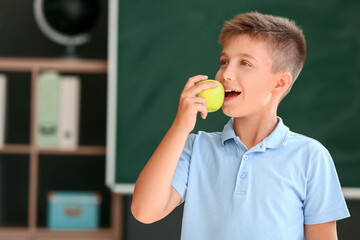 Sticker - Schoolboy eating apple against blurred background in school