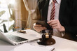 © NINENII - Justice and law concept.Male judge in a courtroom the gavel, working with digital tablet computer on wood table in sun light.