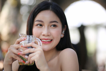 Beautiful young woman smiling while holding a glass of water at home. Lifestyle concept