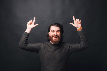 Wall Mural - Photo of man in casual pointing up over black background.