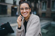 © Roman - Good-looking dark-haired Caucasian girl wearing glasses, speaking on the phone and smiling sweetly. Good vibes. Concept of being in touch using mobile digital device that facilitate communication