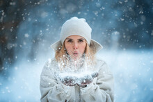 Beautiful Woman Blowing Snow In The Snowy Park
