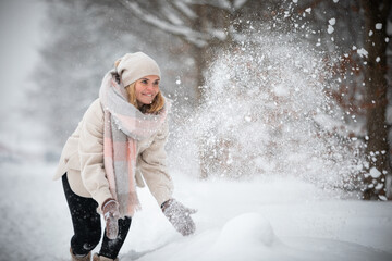 Wall Mural - Winter playing woman throwing up snow in the park