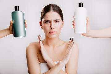 Sticker - Female model in white top refuses to use harmful shampoos. Shot of girl with arms crossed on isolated background