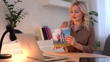 Wall Mural - Close up Young Woman Looking At Photobook, woman presenting photobook near laptop