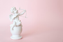 Figurine Of An Angel Cupid With A Bow On A Pink Background. Valentine's Day.