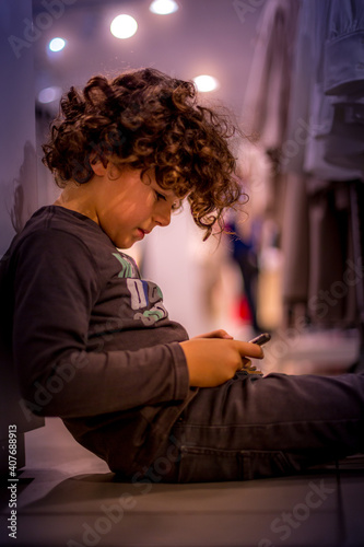 Young boy (4-5) playing mobile game on his parents' phone in a shopping arcade