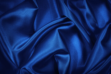 Luxurious blue silk satin background. Soft wavy folds on shiny fabric. Beautiful abstract background with copy space for design.