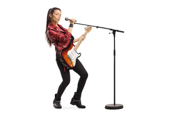 Wall Mural - Young female singer with an electric guitar and a microphone on a stand