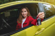 © Taras Grebinets - Young woman holds out the car keys through the driver's seat window. Focus on keys