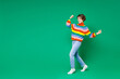 © ViDi Studio - Full length side view of happy joyful young brunette woman 20s in colorful sweater doing winner gesture celebrating clenching fists say yes isolated on bright green color background studio portrait.