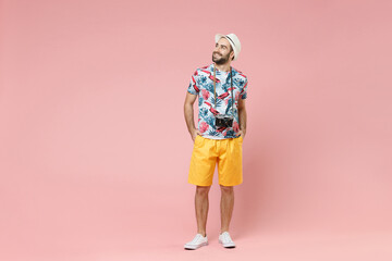 Wall Mural - Full length funny young traveler tourist man in summer clothes hat with photo camera looking aside up isolated on pink background studio. Passenger traveling on weekends. Air flight journey concept.