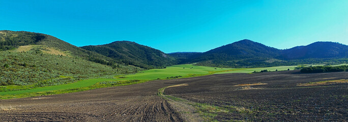 Poster - Panoramic shot of agricultural fields surrounded by mountains under the  sky