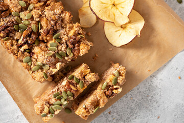 Gluten-free apple cake with walnuts, pumpkin seeds, cinnamon, and nutmeg. Freshly baked apple cake on baking paper top view. Sweet vegetarian food, vegan dessert.