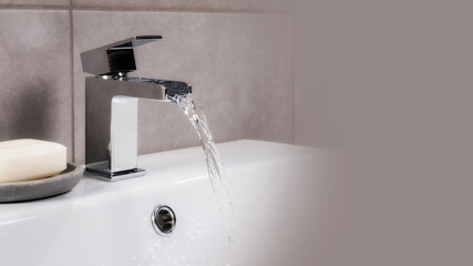 Wall Mural - Closeup shot of water flowing from a basin mixer tap in the bathroom