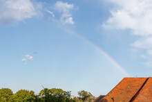 Cute Rainbow Over A House With A Red Tile Roof Above Some Large Trees