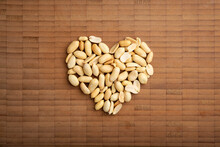 Love Concept Image Of Heart Shape Made Of Peeled Peanuts On Bamboo Cutting Board Background