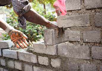 Canvas Print - Closeup shot of a worker make a concrete wall with cement brick