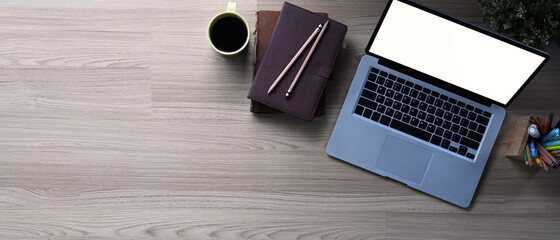 Top view of entrepreneur table with open laptop computer, notebook and coffee cup on wooden table. Copy space for text information or content.