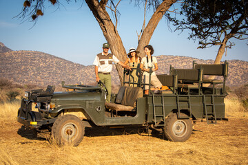 Wall Mural - Guide and brunettes under tree in jeep