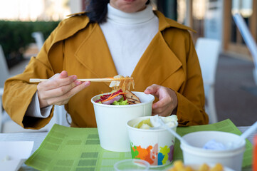 Wall Mural - Woman having noodles meal in the restaurant from the paper box