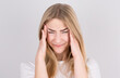 © Studio Nova - Young woman with a headache holds her temples with her hands. Health, migraine and headache concept.