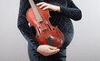 © rubchikova - Pregnant woman with red violin isolated on gray background.