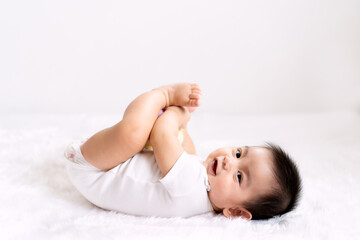 a cute 6 months old asian little baby boy is playing his hands and feet with fully happiness moment 
