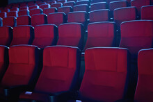 Close Up Shot Of Interior Of Cinema Auditorium With Lines Of Red Chairs In Front Of A Big Screen