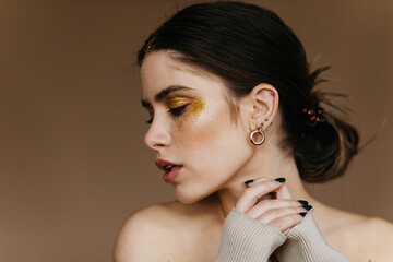 Poster - Fascinating woman with party makeup posing in studio. Indoor close-up photo of relaxed brunette girl wears earrings.