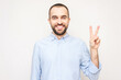 Bearded man shows sign peace with fingers, white background, copy space