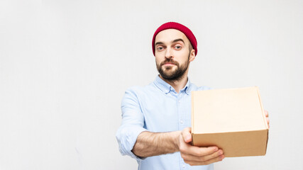 Attractive bearded man shows cardboard box, portrait, white background, copy space, 16:9