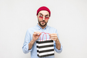 Wall Mural - Funny bearded with package purchases, man heart-shaped glasses smiles, white background, copy space