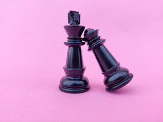 Black chess queen fallen on black chess king's shoulder. Valentines day concept