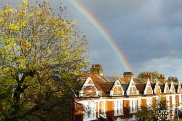 London, England - A double rainbow appearing to end behind a row of typical English terraced houses, against a stormy grey sky.  Image has copy space.