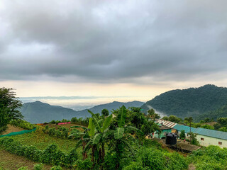 Poster - Beautiful shot of tropical landscape and houses on background of green mountains and a cloud sky