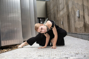 White woman in black clothes sitting in city lane on paving stones