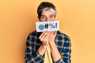 Wall Mural - Young hispanic man covering mouth with insult message paper covering mouth with hand, shocked and afraid for mistake. surprised expression