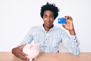 Poster - Handsome african american man with afro hair holding credit card and piggy bank depressed and worry for distress, crying angry and afraid. sad expression.