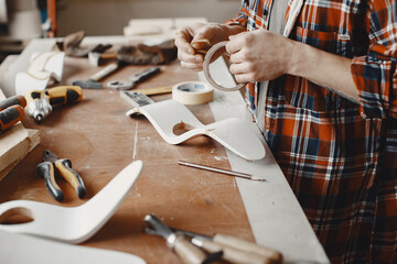 Wall Mural - Craftsman cutting a wooden plank. Worker with wood. Man in a cell shirt.