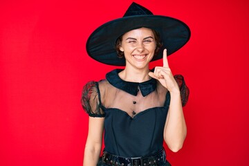 Poster - Young hispanic woman wearing witch halloween costume pointing finger up with successful idea. exited and happy. number one.