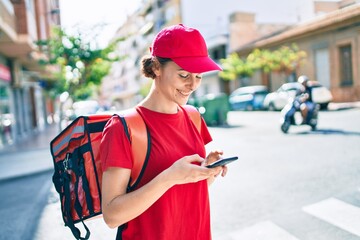 Delivery business worker woman wearing uniform and delivery bag smiling happy using phone