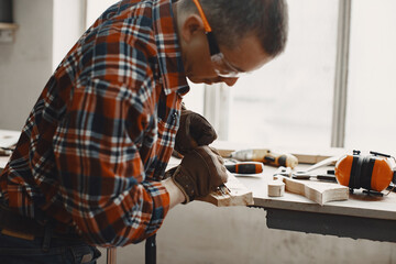 Wall Mural - Craftsman cutting a wooden plank. Worker with wood. Man in a cell shirt.