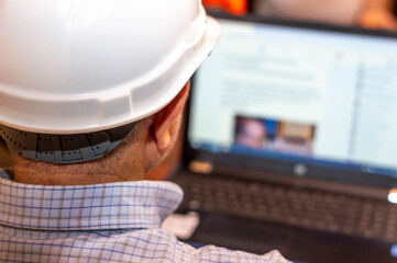 Engineer man with white helmet looking at his laptop