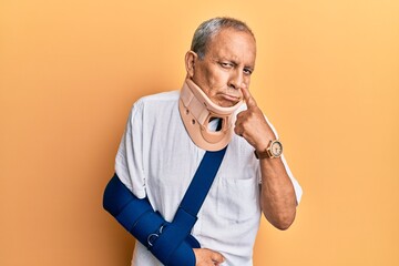 Canvas Print - Handsome mature senior man wearing cervical collar and arm on sling pointing to the eye watching you gesture, suspicious expression