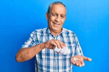 Poster - Senior hispanic man holding pills smiling with a happy and cool smile on face. showing teeth.