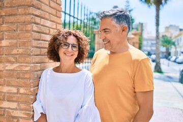 Poster - Middle age couple smiling happy leaning on the wall at street of city.