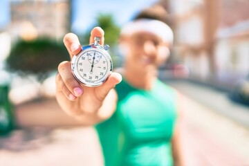 Wall Mural - Young hispanic sportsman smiling happy holding stopwatch at street of city