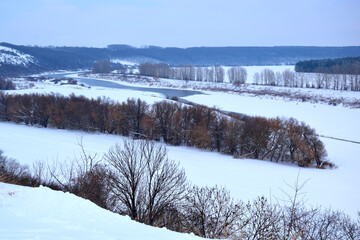 View from the mountain to the snow-covered river and fields