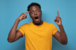 © Viktor Koldunov - Young handsome african man pointing with finger up having great idea for start up. Studio shot on blue wall